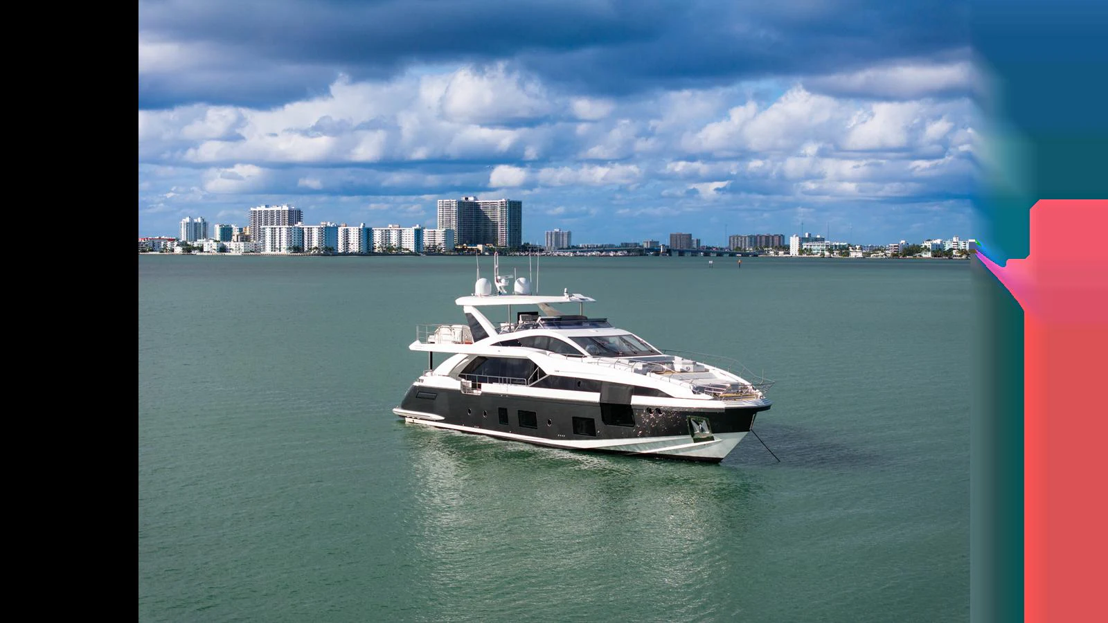 A sleek and modern yacht cruises gracefully on calm waters with a cityscape in the background. aboard CLOUD 9 Yacht for Sale