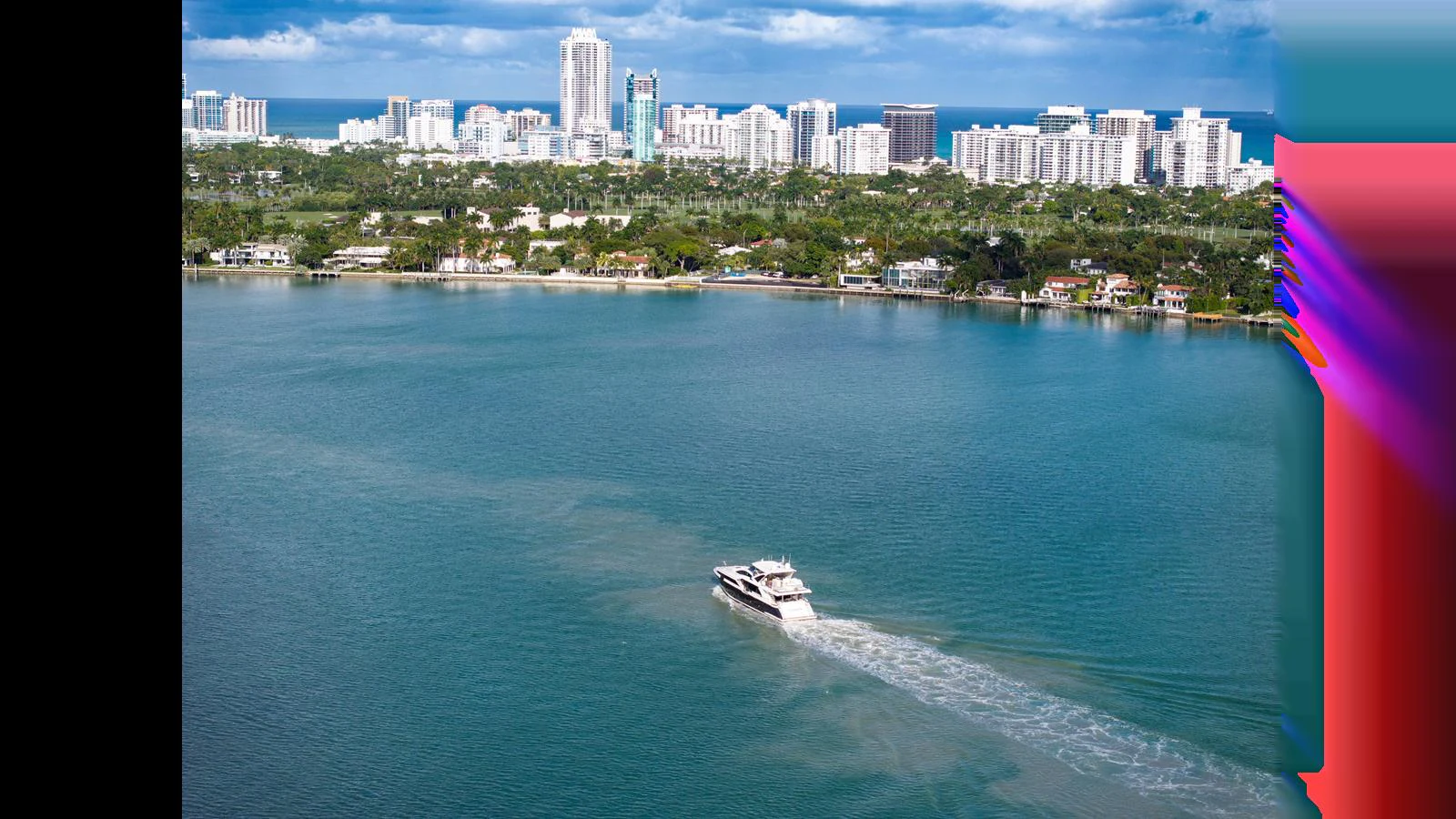A yacht cruises through calm waters with a cityscape in the background. aboard CLOUD 9 Yacht for Sale