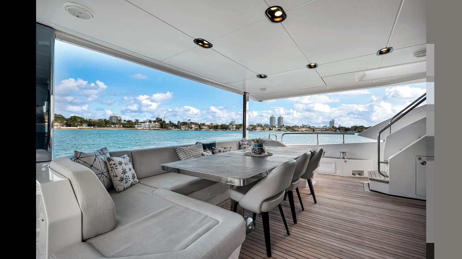 The aft deck features a spacious seating area with a dining table, offering stunning views of the water. aboard CLOUD 9 Yacht for Sale