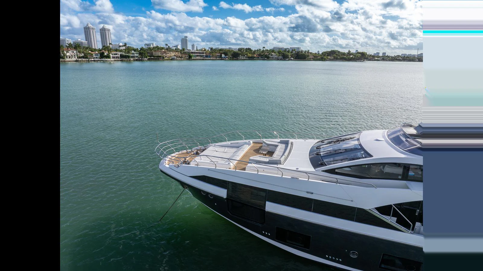 A sleek yacht cruises along a calm waterfront under a bright sky. aboard CLOUD 9 Yacht for Sale
