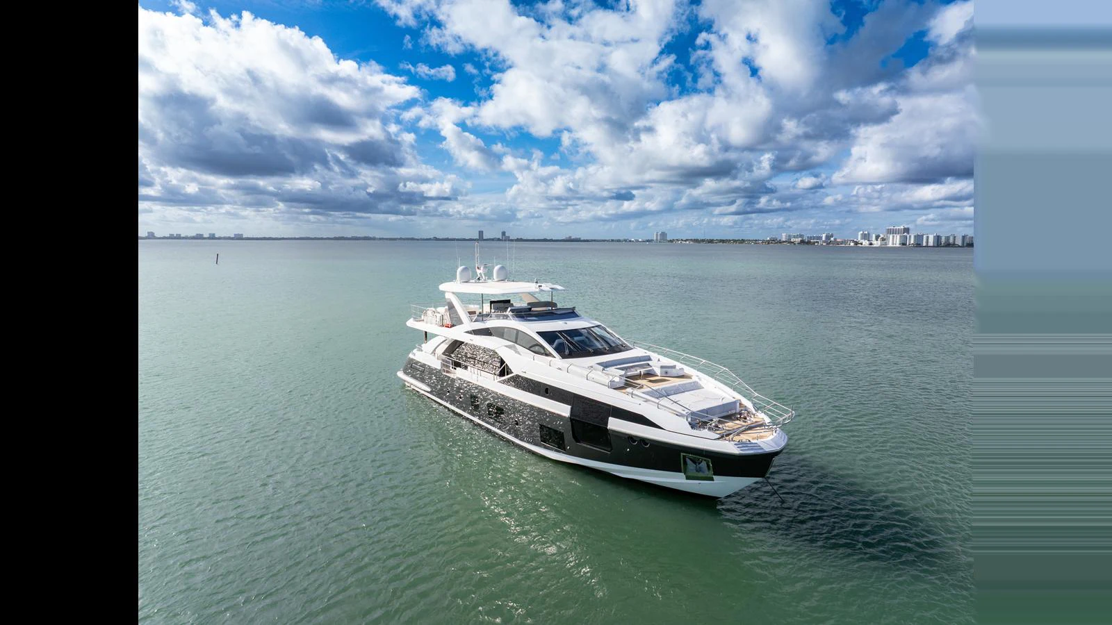 A luxurious yacht cruises on calm waters under a partly cloudy sky. aboard CLOUD 9 Yacht for Sale