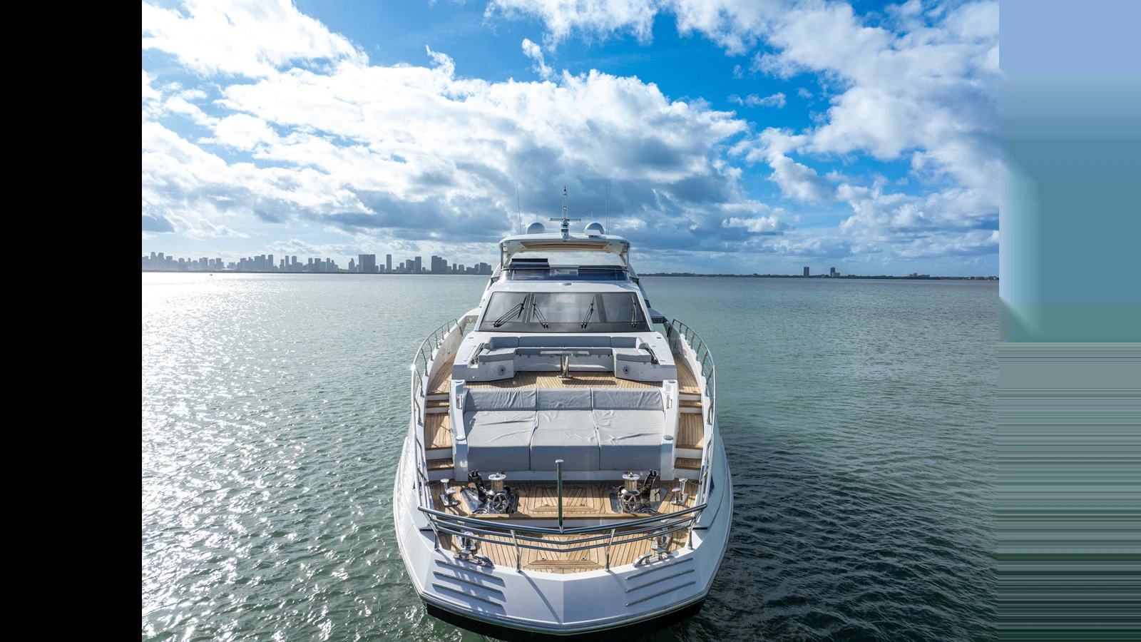 A luxurious yacht is anchored on calm waters with a city skyline in the background. aboard CLOUD 9 Yacht for Sale