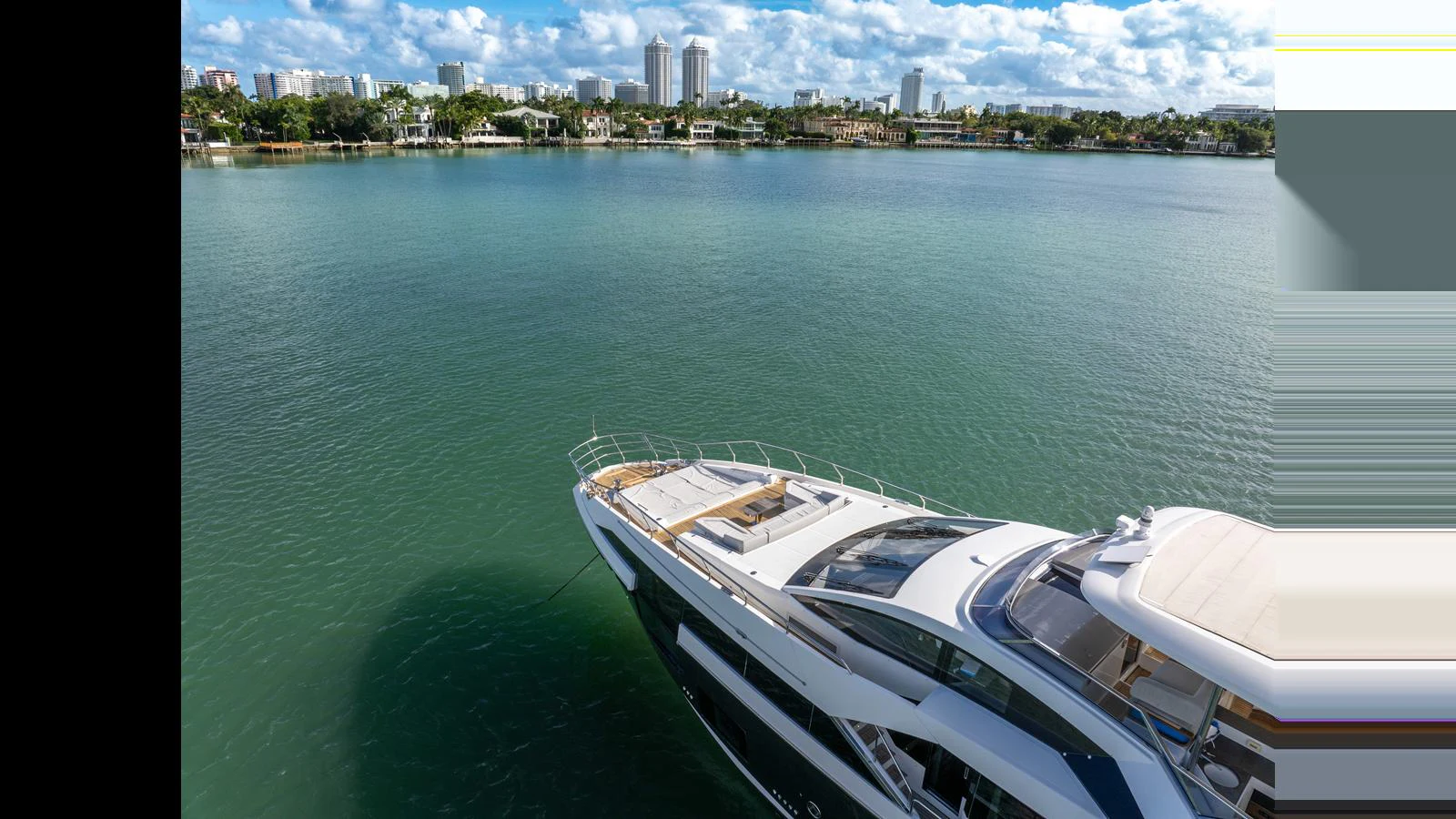 A sleek yacht cruises through calm waters with a cityscape in the background. aboard CLOUD 9 Yacht for Sale