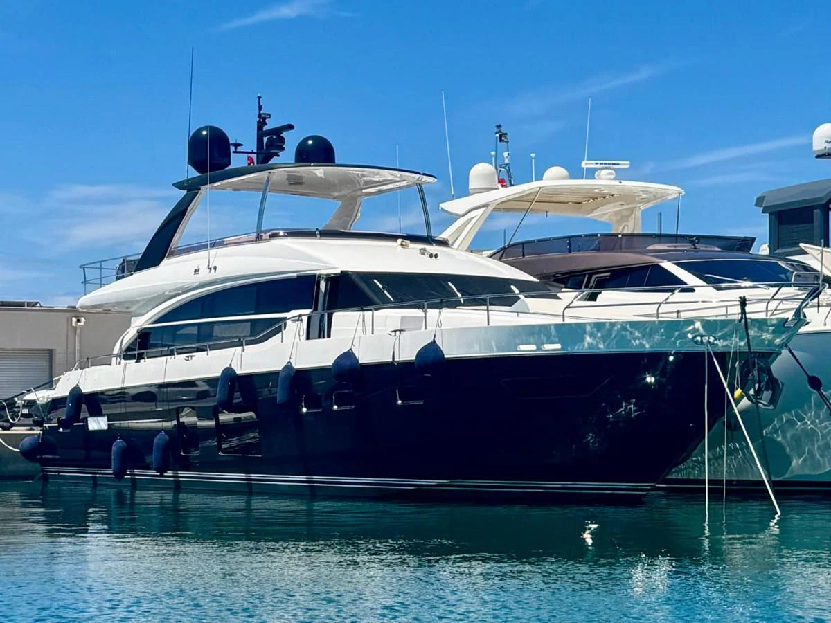 A sleek and modern yacht is docked in a serene marina under a clear blue sky. aboard LADY N Yacht for Sale