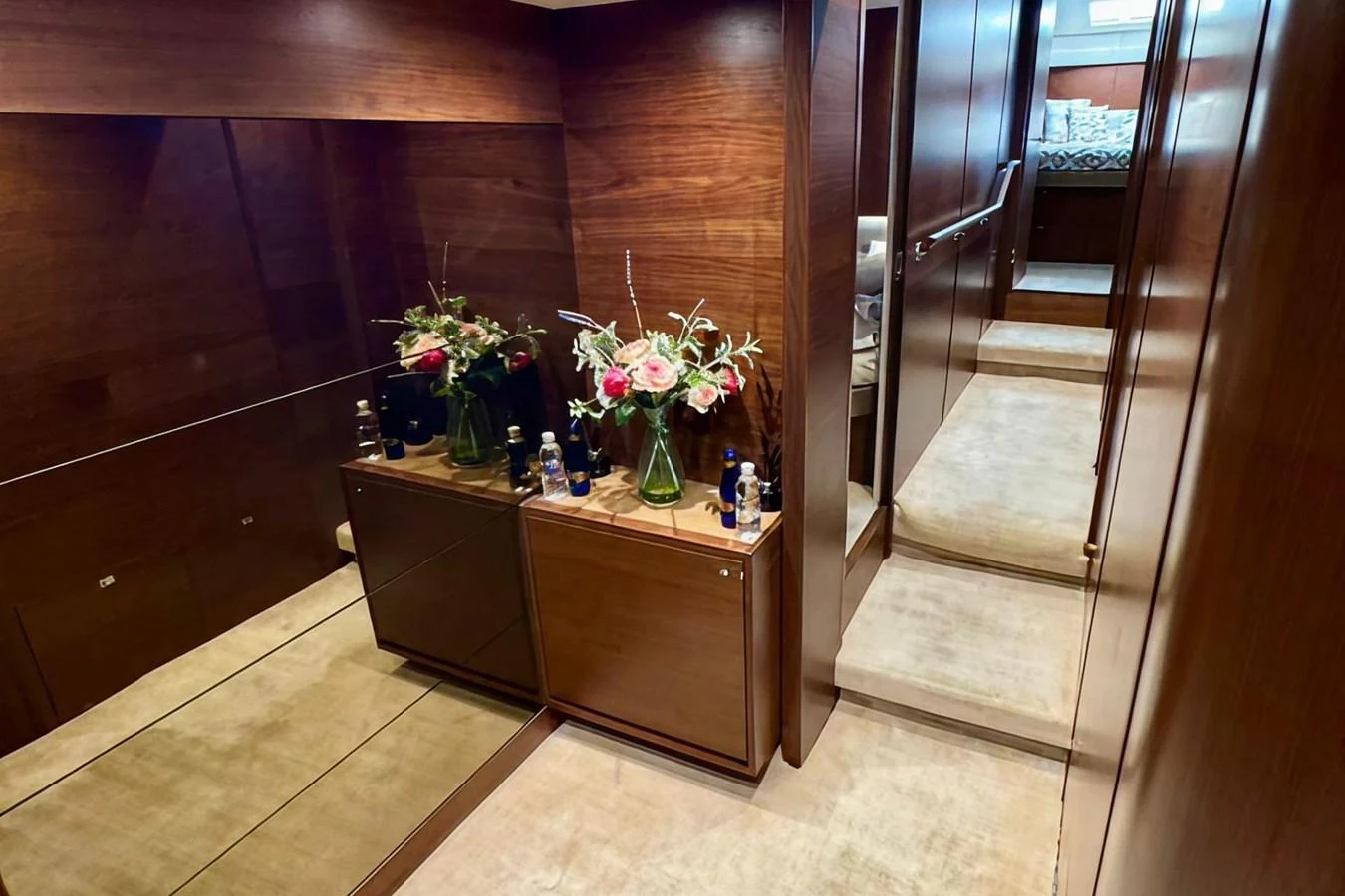 The yacht's interior features a hallway with elegant wood paneling and a mirrored wall, leading to a cozy stateroom. aboard LADY N Yacht for Sale