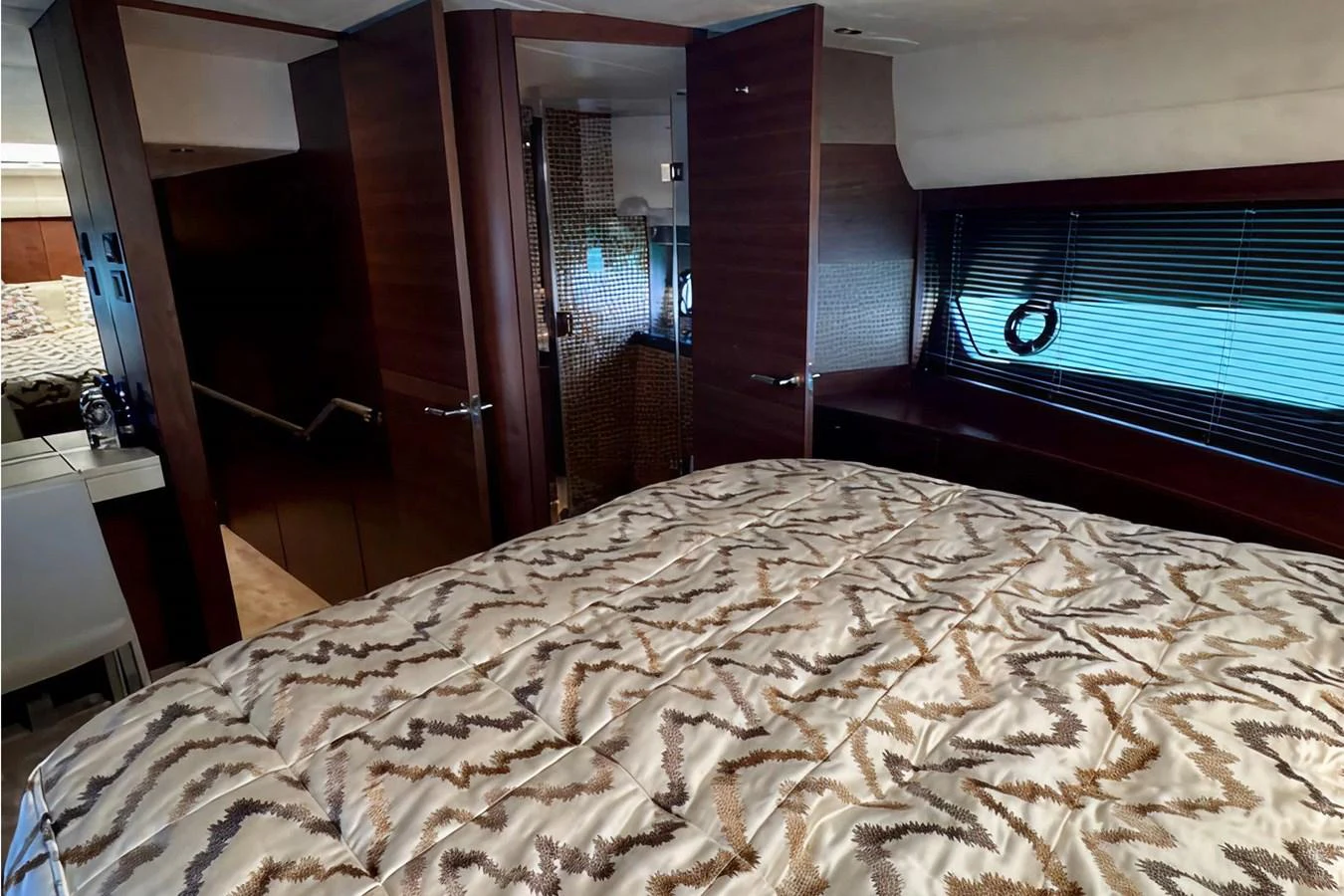 The stateroom features a comfortable bed with patterned bedding and ample natural light from the window. aboard LADY N Yacht for Sale