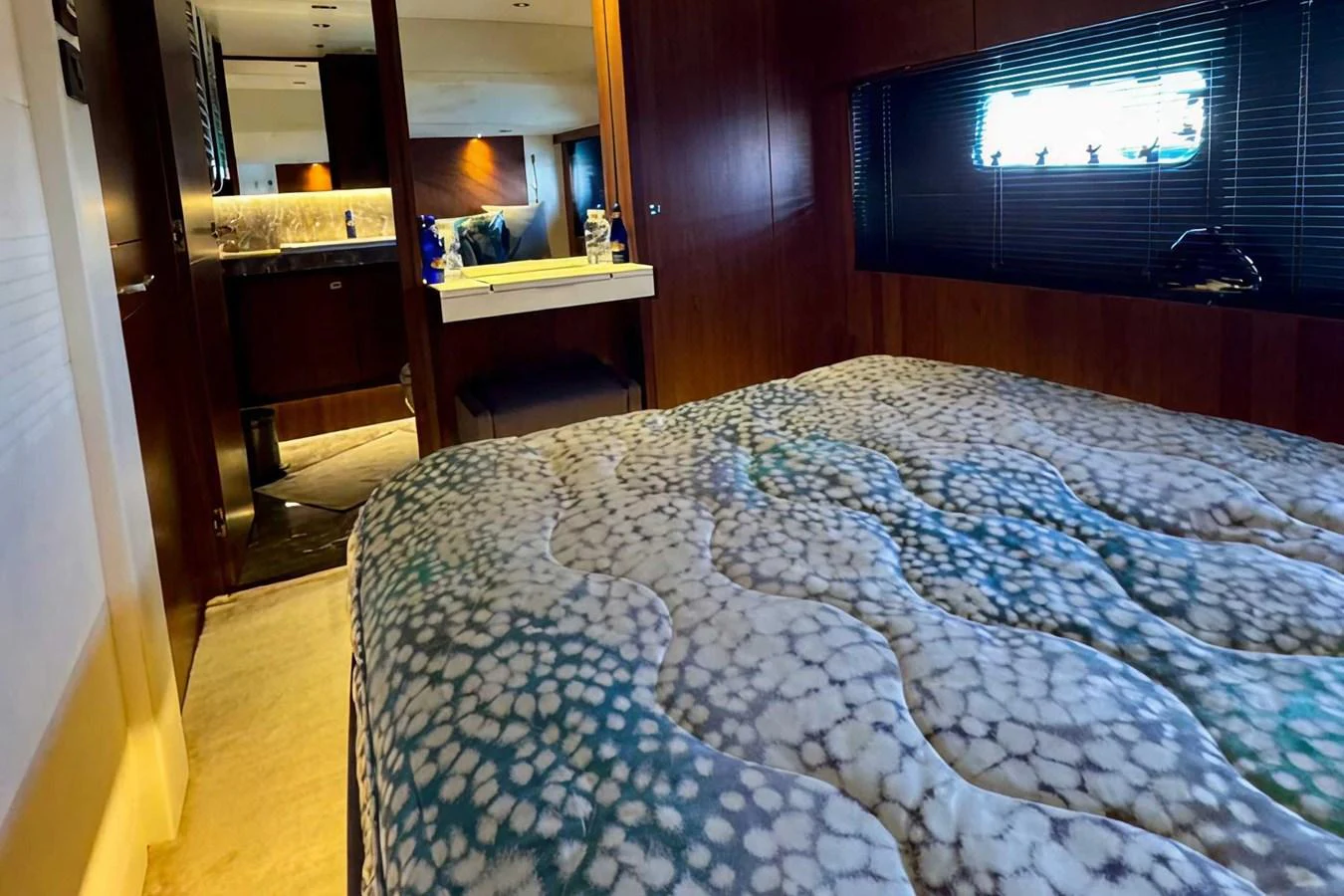 A cozy stateroom featuring a plush bed with patterned bedding and a view into the adjoining bathroom. aboard LADY N Yacht for Sale