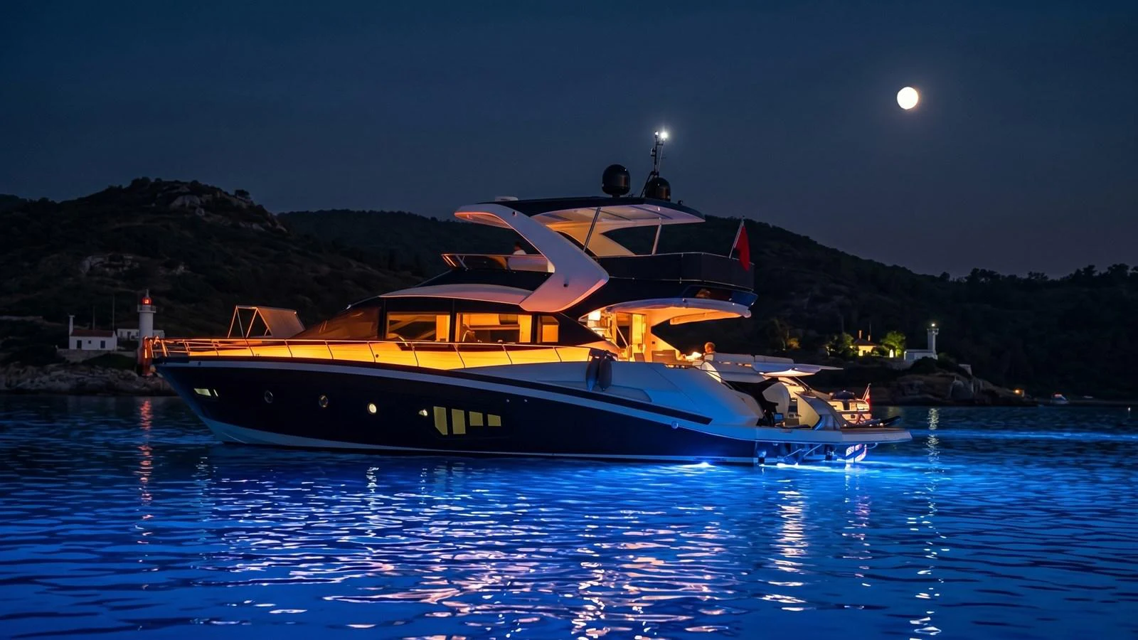 A luxurious yacht is beautifully illuminated at night, anchored in serene waters under a full moon. aboard ASB Yacht for Sale