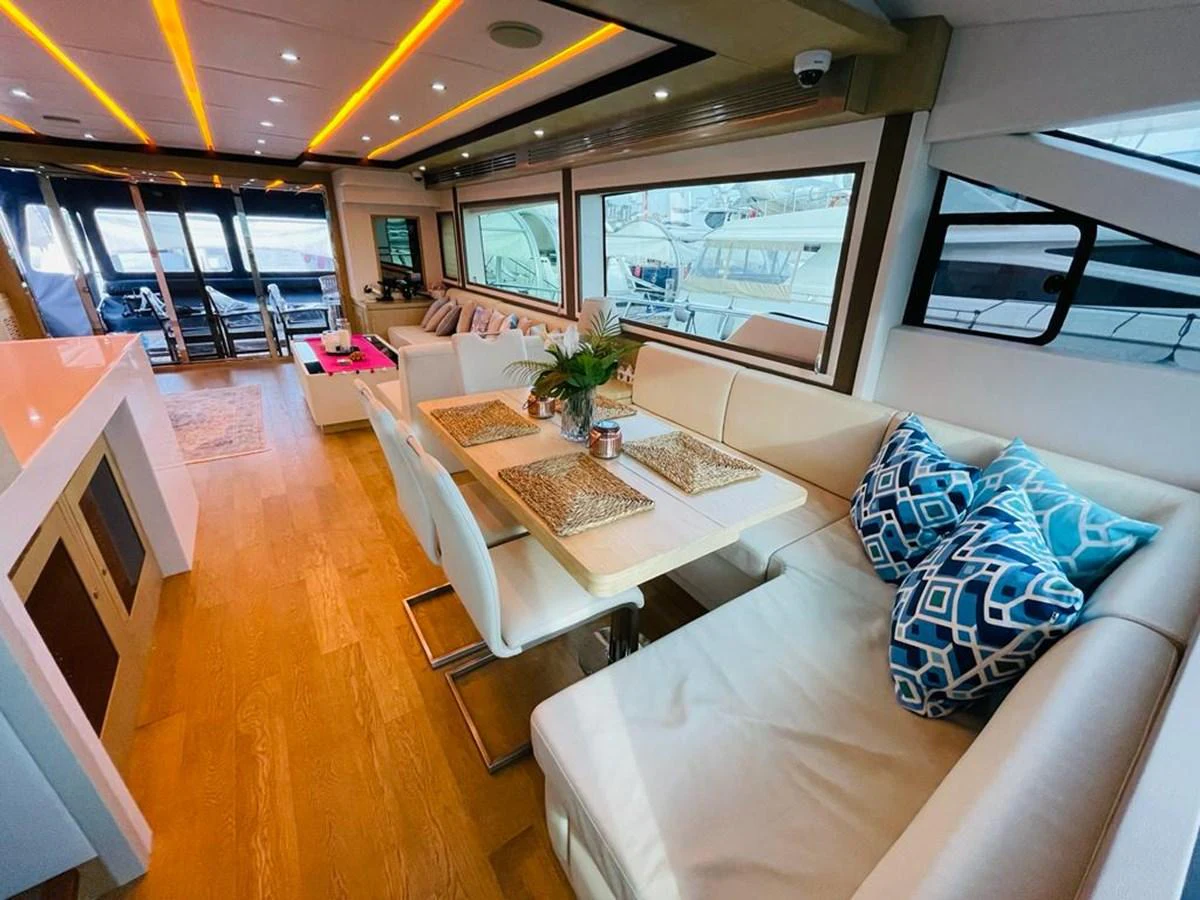 The salon features a spacious seating area with a dining table and modern decor. aboard ASB Yacht for Sale