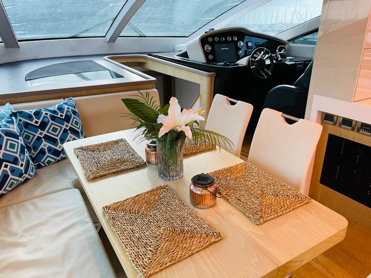 The yacht's dining area features a cozy table setting with a view of the helm station. aboard ASB Yacht for Sale