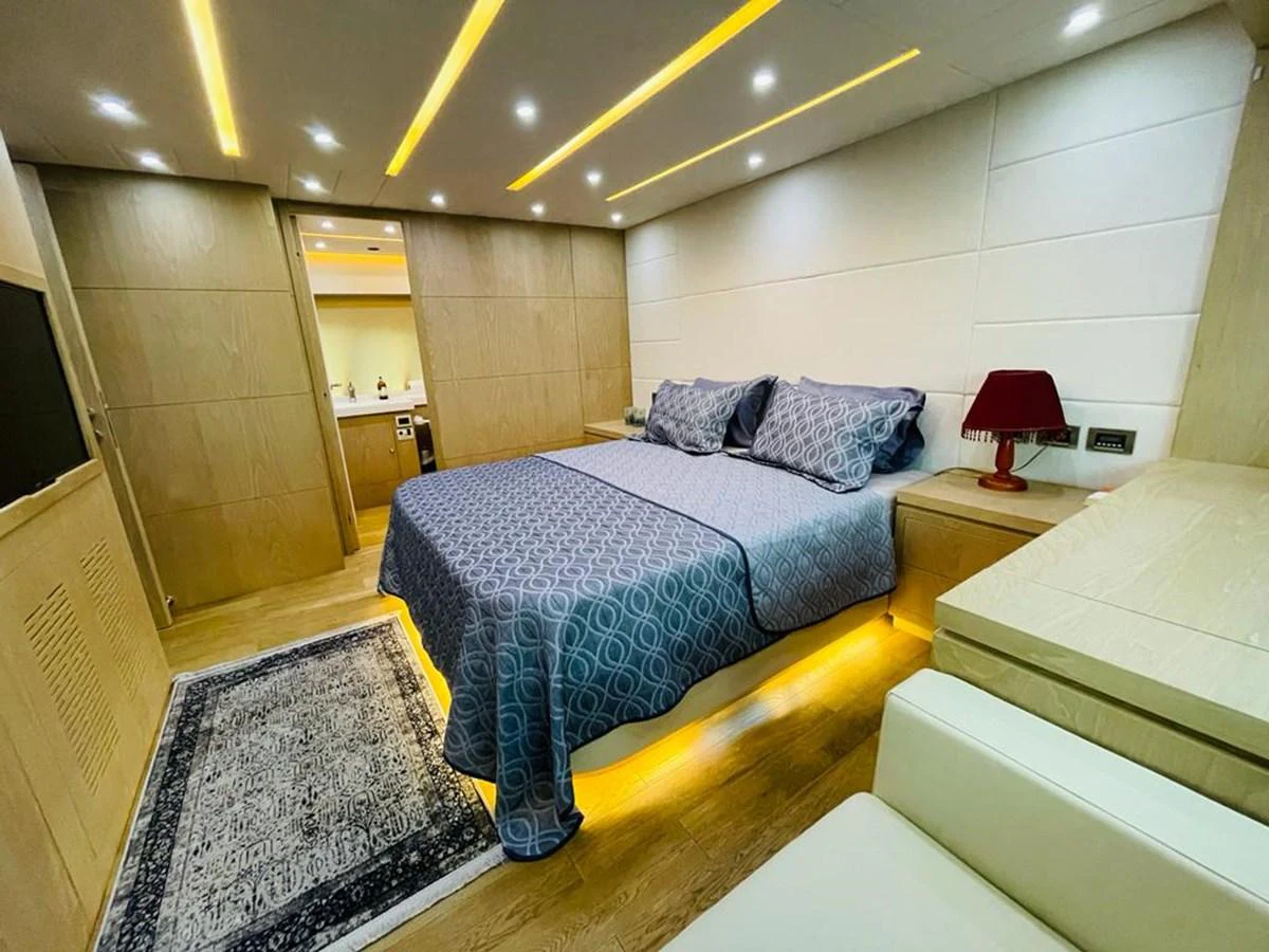 The stateroom features a cozy bed with elegant bedding and ambient lighting. aboard ASB Yacht for Sale