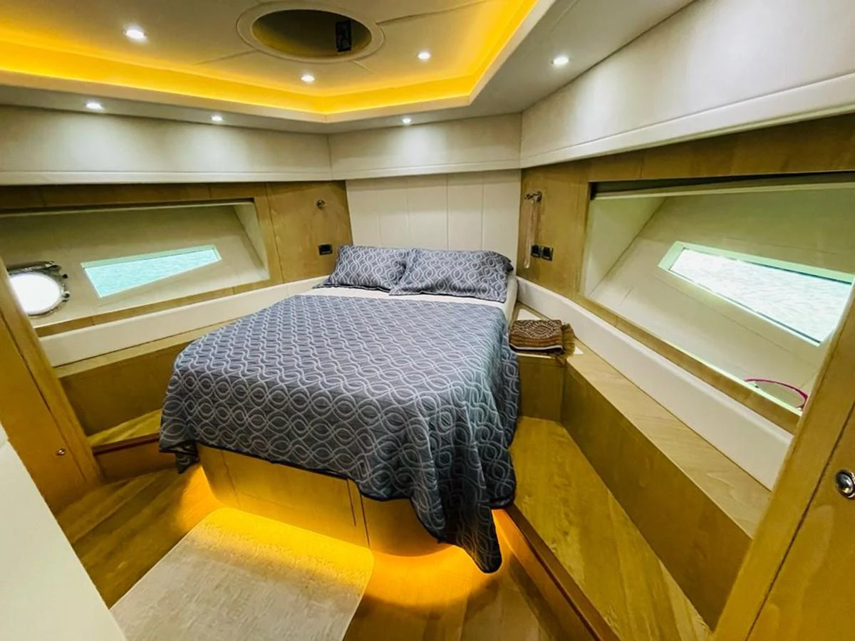 A cozy stateroom featuring a comfortable bed with ambient lighting and large windows offering natural light. aboard ASB Yacht for Sale