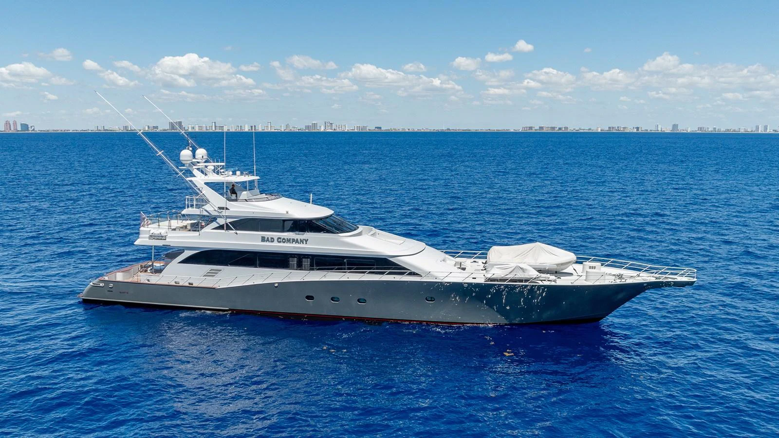 A sleek and modern yacht glides effortlessly on the open sea under a clear blue sky. aboard BAD COMPANY Yacht for Sale