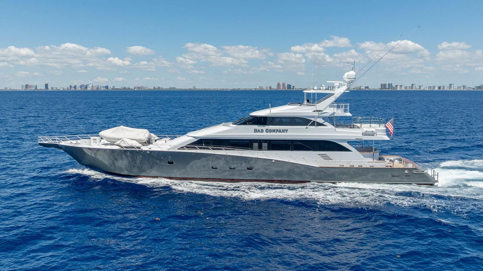 A sleek and luxurious yacht cruising on a calm blue sea under a clear sky. aboard BAD COMPANY Yacht for Sale