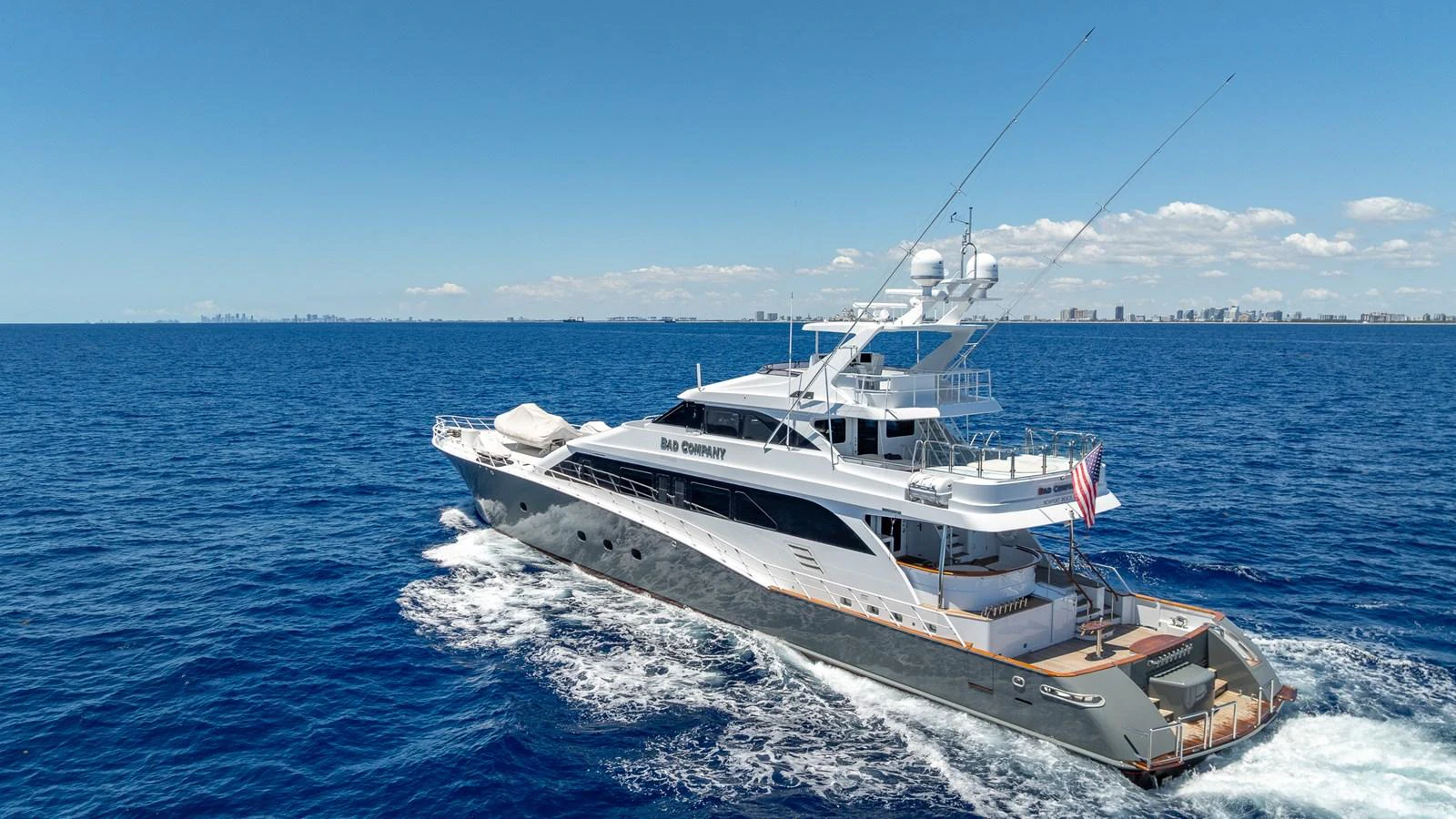 A sleek yacht cruises through the open sea under a clear blue sky. aboard BAD COMPANY Yacht for Sale