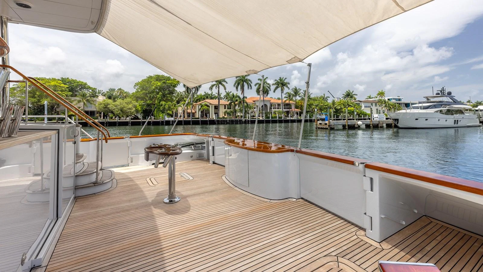 The yacht's aft deck features a spacious and shaded area with elegant teak flooring and a scenic waterfront view. aboard BAD COMPANY Yacht for Sale
