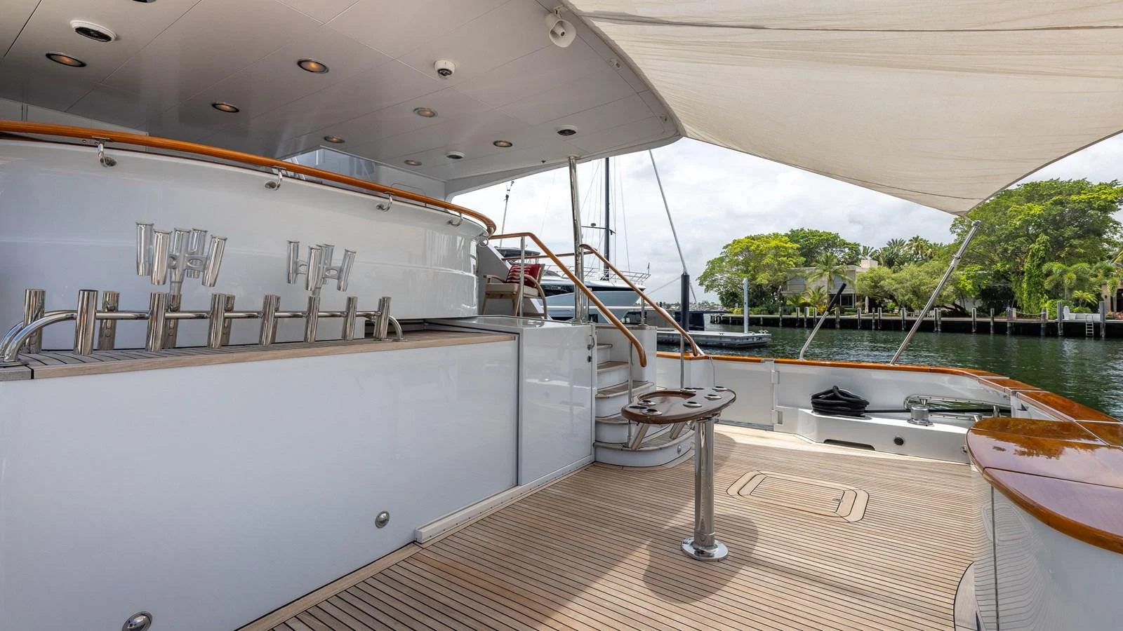 The aft deck features a sleek bar area with modern fixtures and ample seating space under a shaded canopy. aboard BAD COMPANY Yacht for Sale