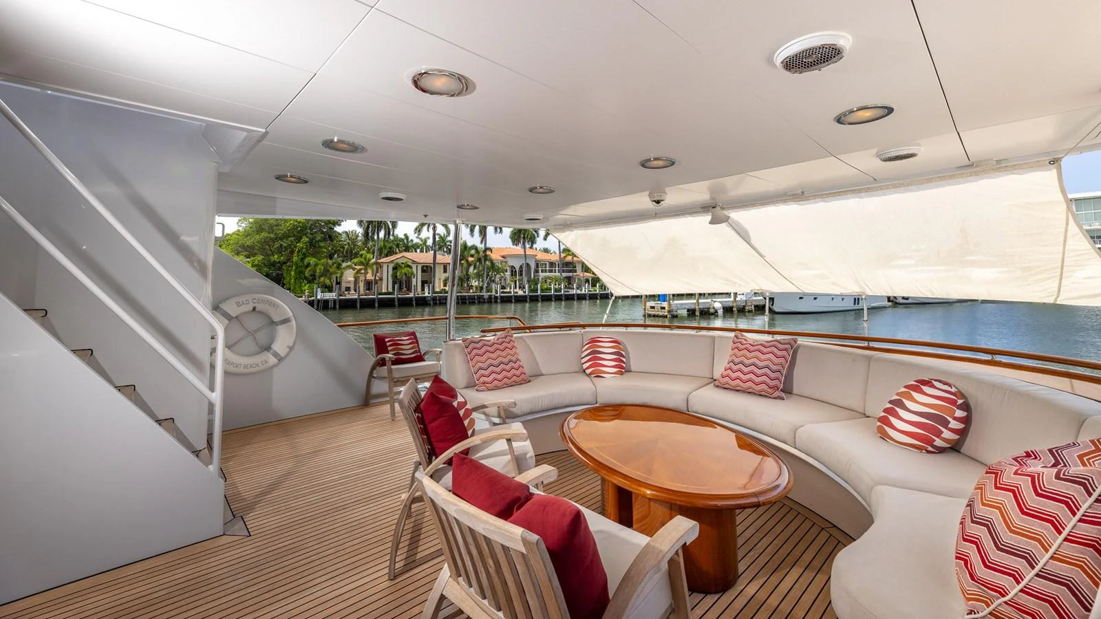 The aft deck features a spacious seating area with a wooden table and comfortable chairs, perfect for relaxation and socializing. aboard BAD COMPANY Yacht for Sale