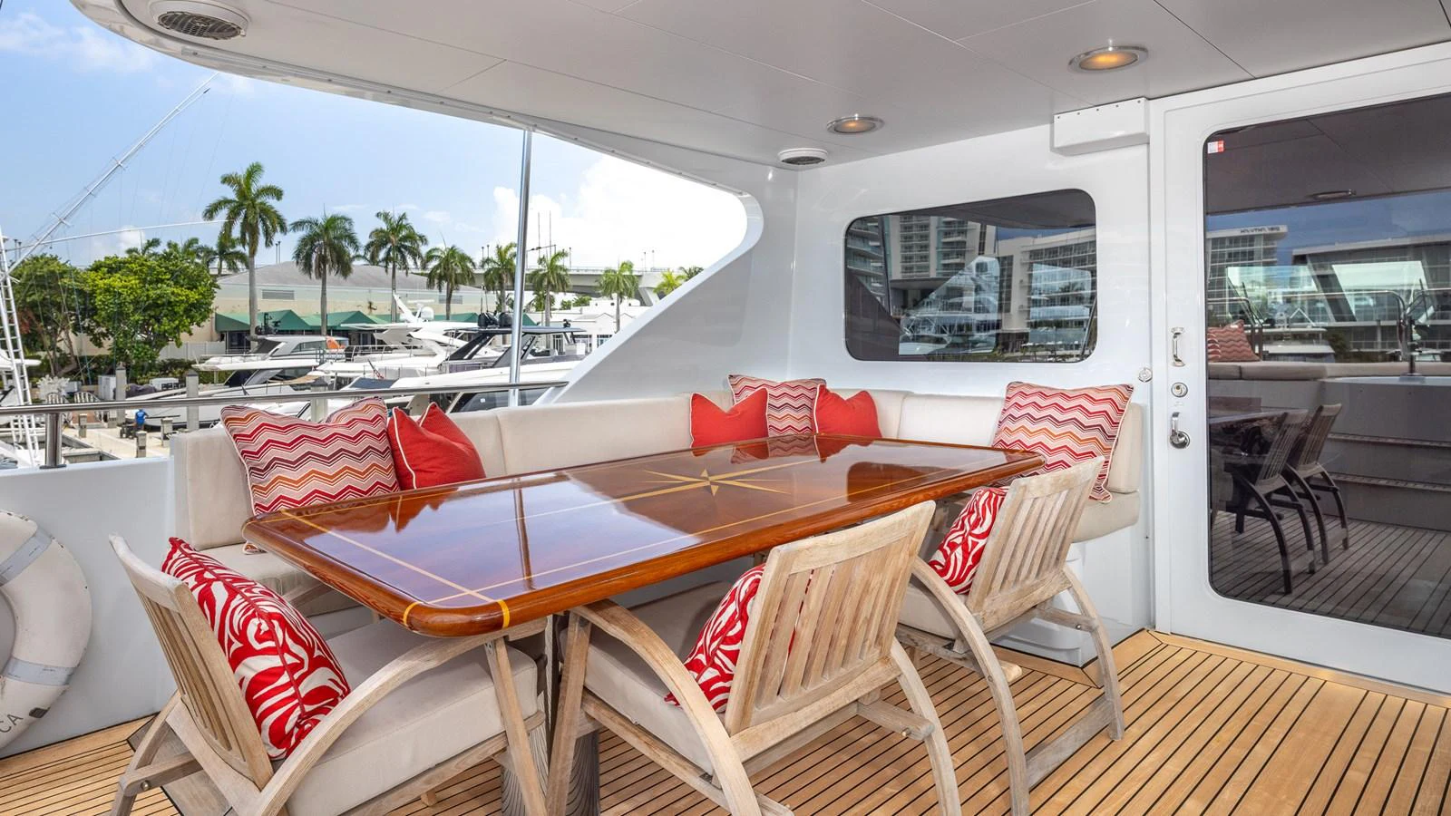 The aft deck features a stylish dining area with a polished wooden table and comfortable seating, perfect for alfresco meals. aboard BAD COMPANY Yacht for Sale