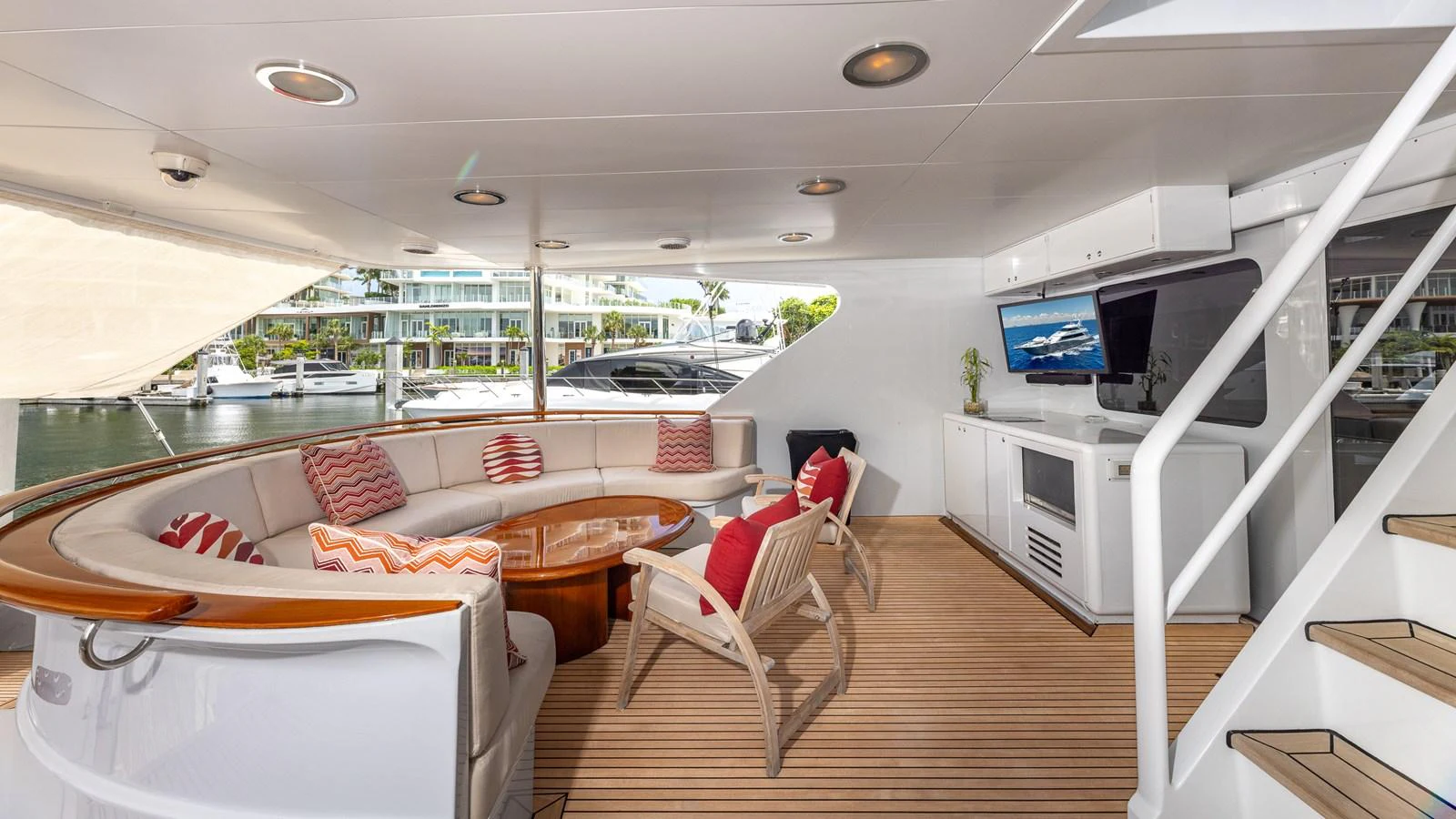 The aft deck features a cozy seating area with a semi-circular sofa, wooden table, and modern amenities. aboard BAD COMPANY Yacht for Sale