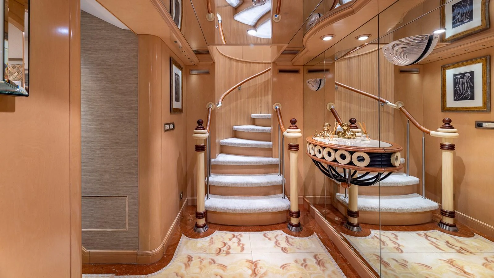 The yacht's interior features an elegant staircase with luxurious finishes and mirrored walls. aboard BAD COMPANY Yacht for Sale