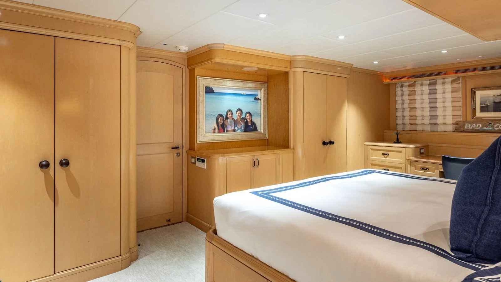The stateroom features elegant wood cabinetry and a comfortable bed with nautical-themed bedding. aboard BAD COMPANY Yacht for Sale