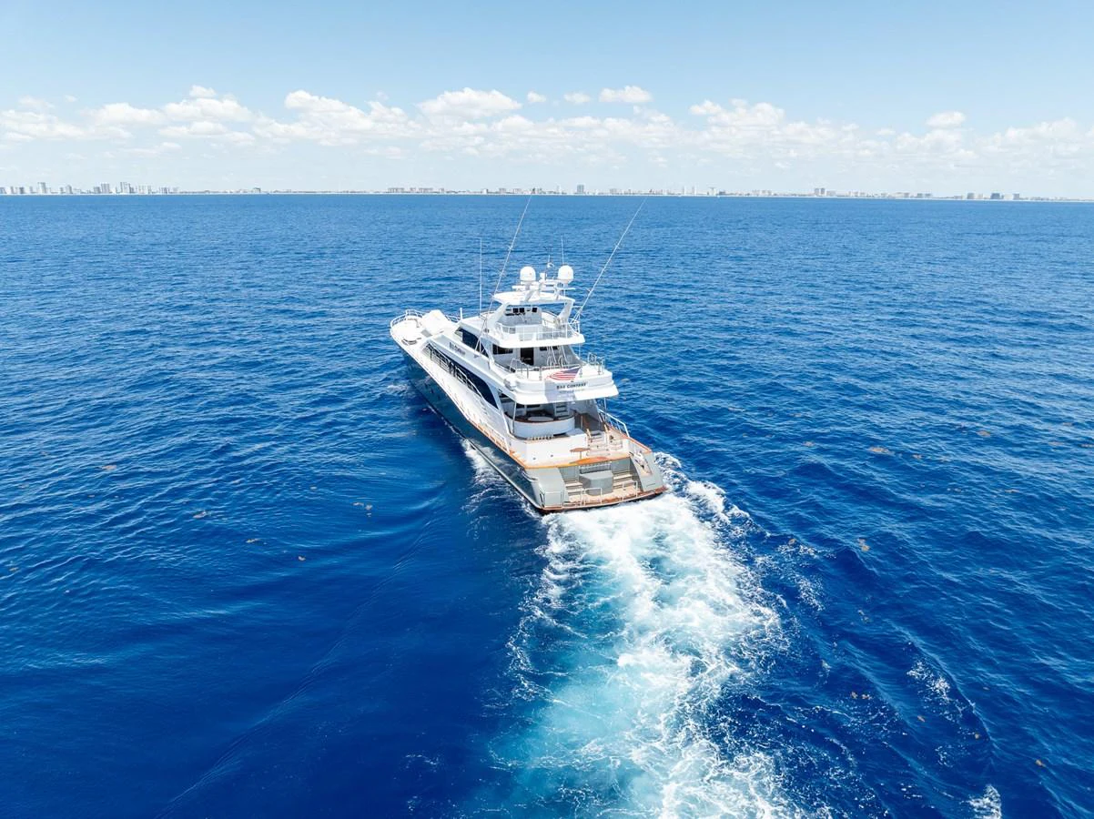 A sleek yacht cruises through the open ocean under a clear blue sky. aboard BAD COMPANY Yacht for Sale