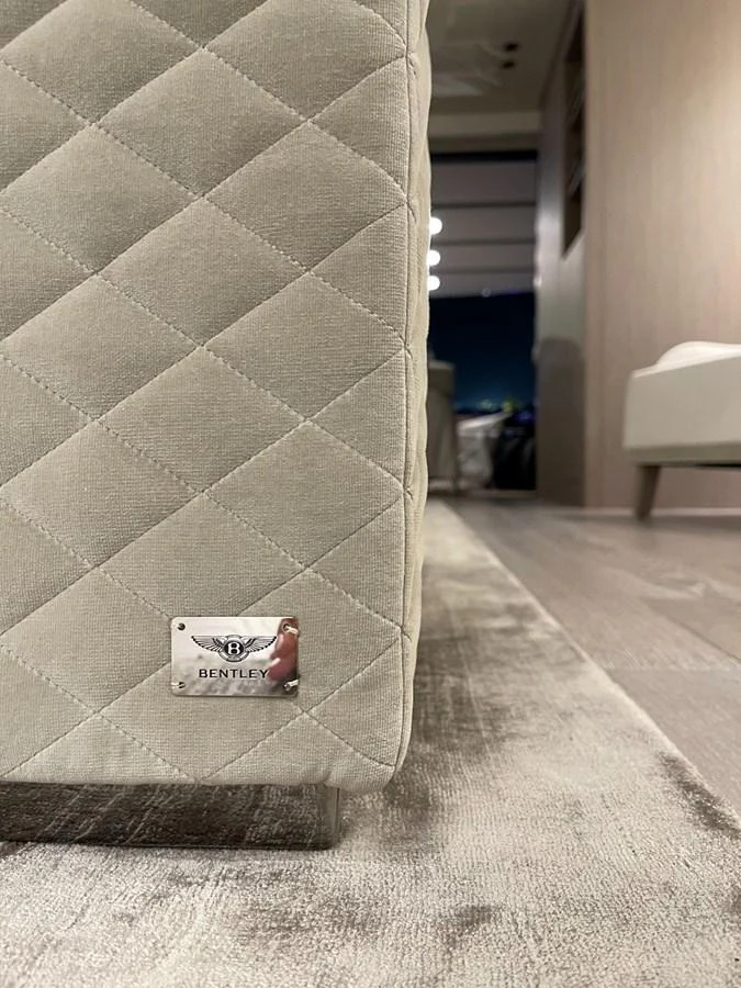 A close-up of a luxurious quilted fabric detail with a Bentley emblem, showcasing the yacht's refined interior craftsmanship. aboard FOUZ Yacht for Sale
