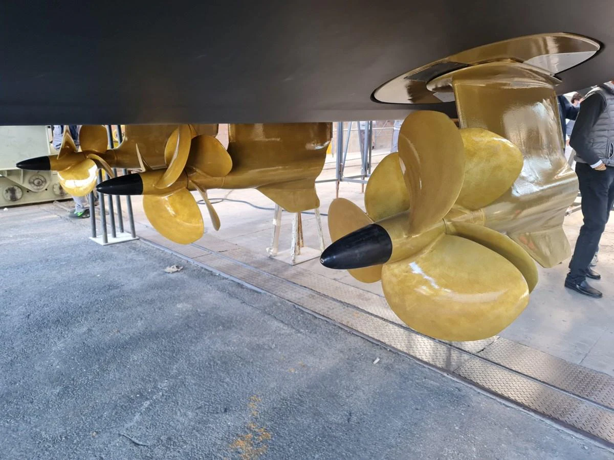 The image showcases the yacht's polished propellers and underwater gear in a dry dock setting. aboard FOUZ Yacht for Sale