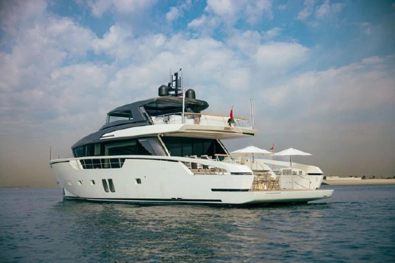 A sleek and modern yacht cruising on calm waters under a partly cloudy sky. aboard FOUZ Yacht for Sale