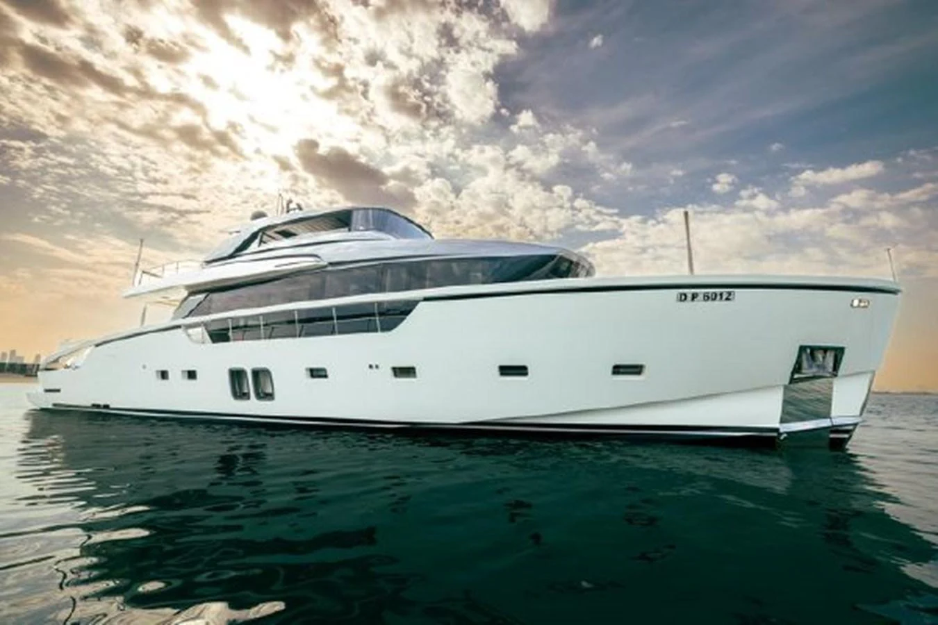 A sleek and modern yacht glides gracefully on calm waters under a dramatic sky. aboard FOUZ Yacht for Sale