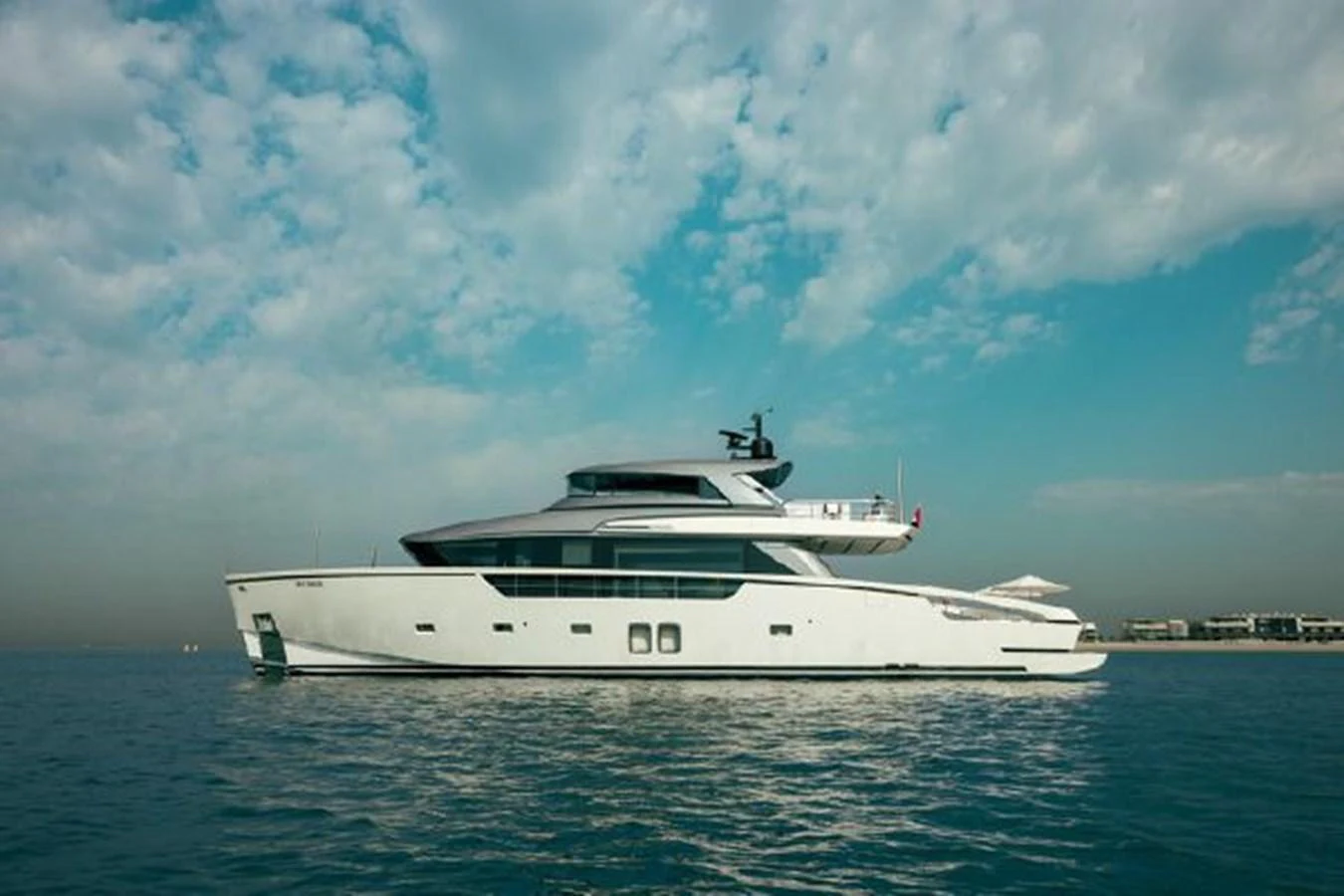 A sleek and modern yacht glides gracefully on calm waters under a partly cloudy sky. aboard FOUZ Yacht for Sale