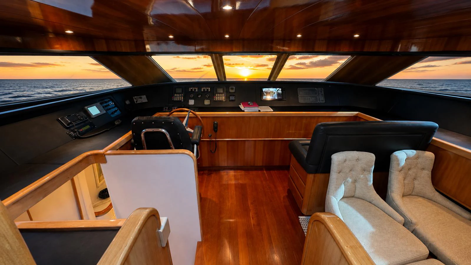 The helm station offers a luxurious and commanding view of the horizon with rich wood finishes and plush seating. aboard ALPHERATZ Yacht for Sale
