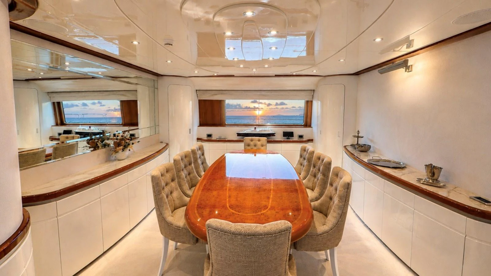 The yacht's dining area features a polished wooden table surrounded by plush chairs, with panoramic windows offering stunning sea views. aboard ALPHERATZ Yacht for Sale