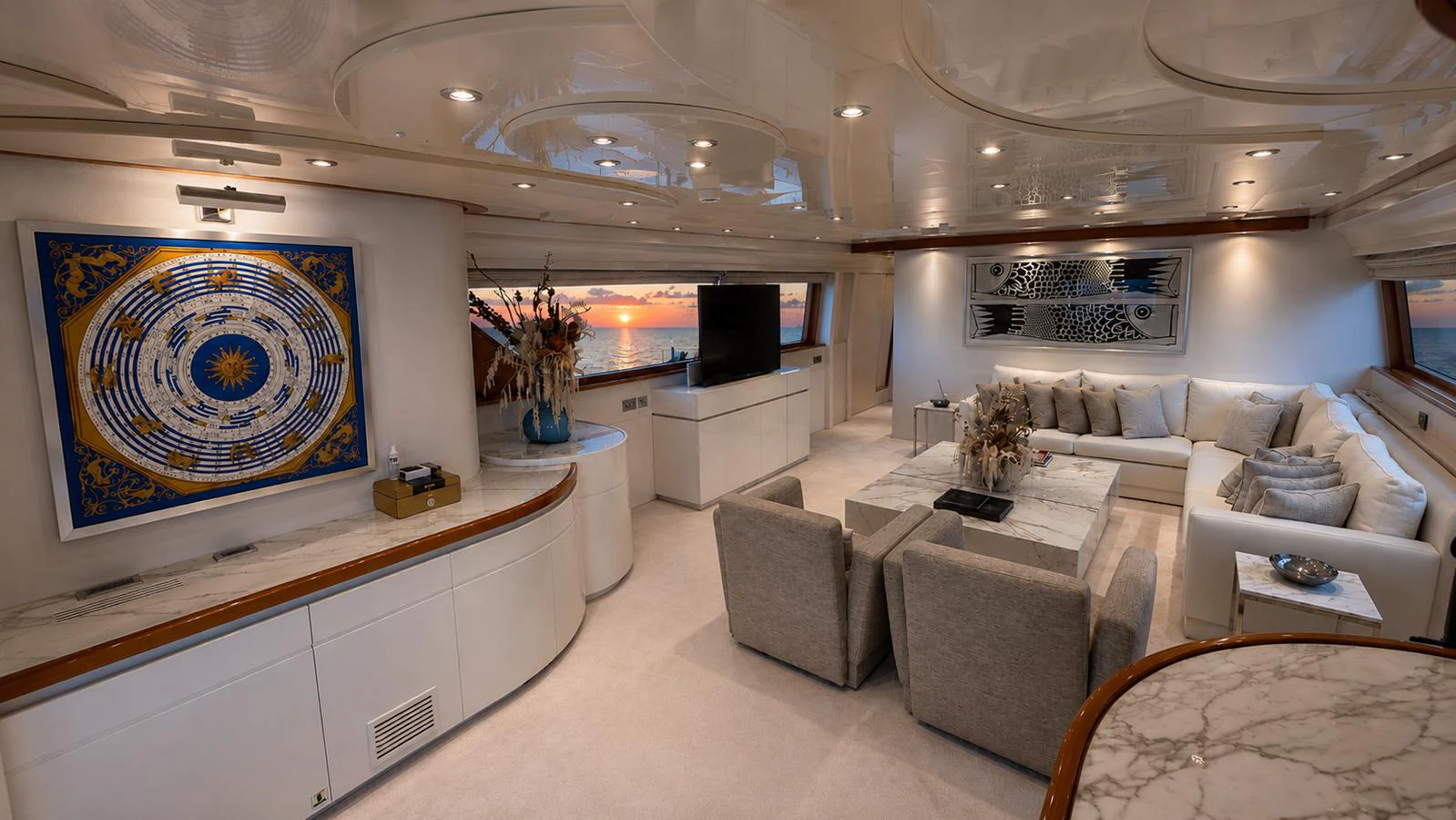 The yacht's salon features elegant seating and modern decor with a stunning view of the sunset. aboard ALPHERATZ Yacht for Sale