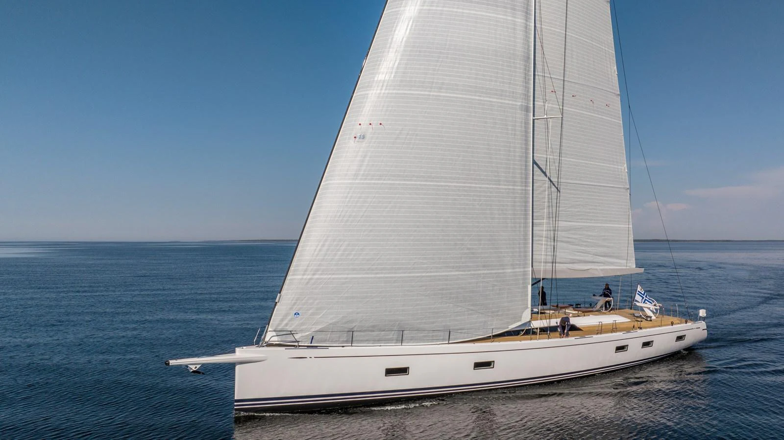 A sleek sailing yacht glides gracefully on calm waters under clear skies. aboard DREAMCATCHER Yacht for Sale