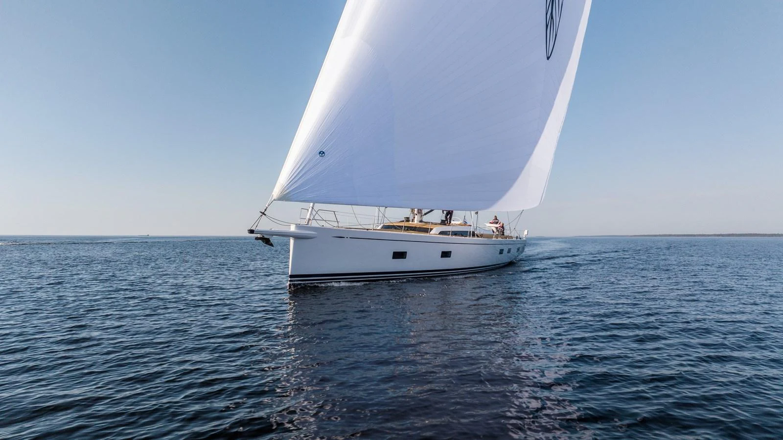 A sleek sailing yacht glides gracefully over calm waters under a clear blue sky. aboard DREAMCATCHER Yacht for Sale