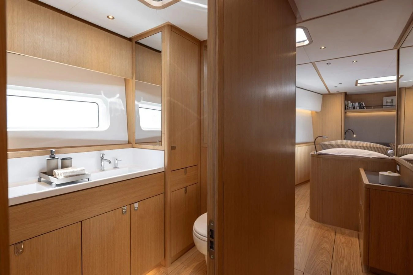 The yacht's bathroom features sleek wooden cabinetry and modern fixtures, leading into a cozy stateroom. aboard DREAMCATCHER Yacht for Sale