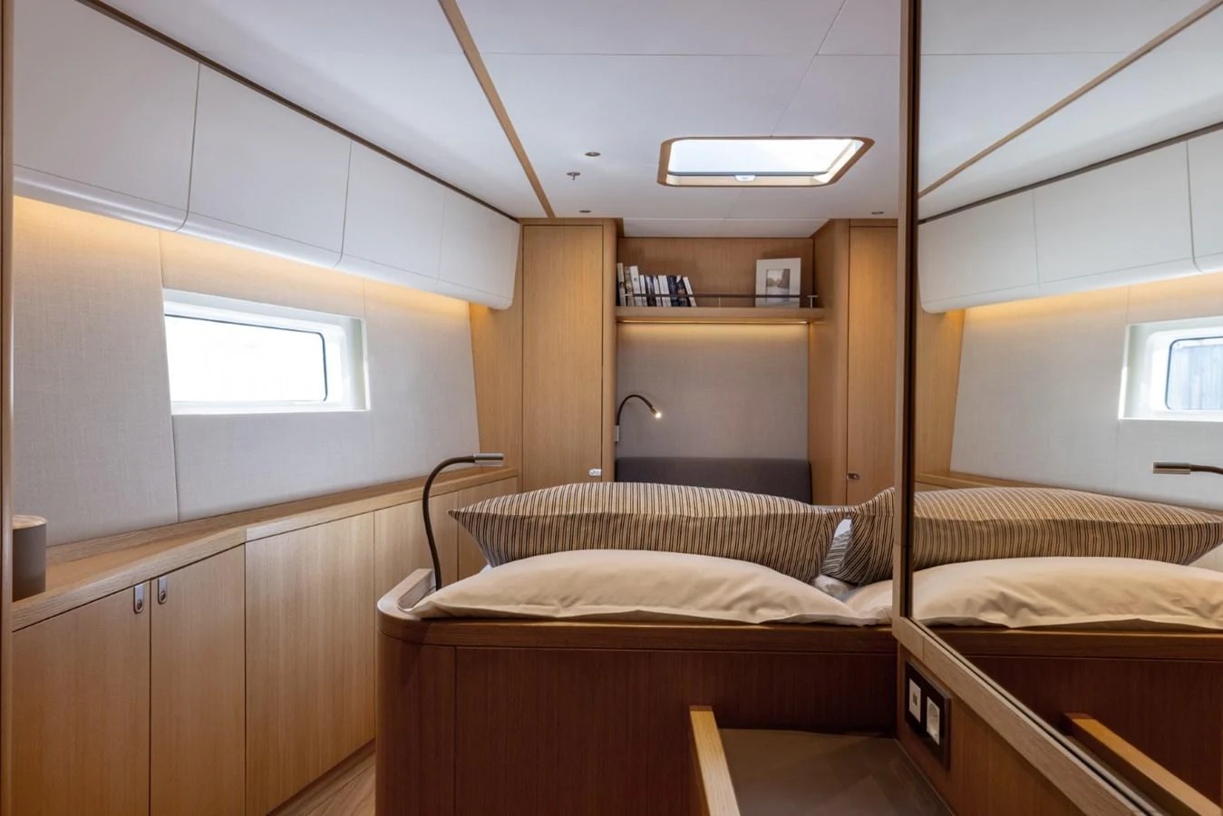A cozy stateroom with a large bed, wooden cabinetry, and a window providing natural light. aboard DREAMCATCHER Yacht for Sale