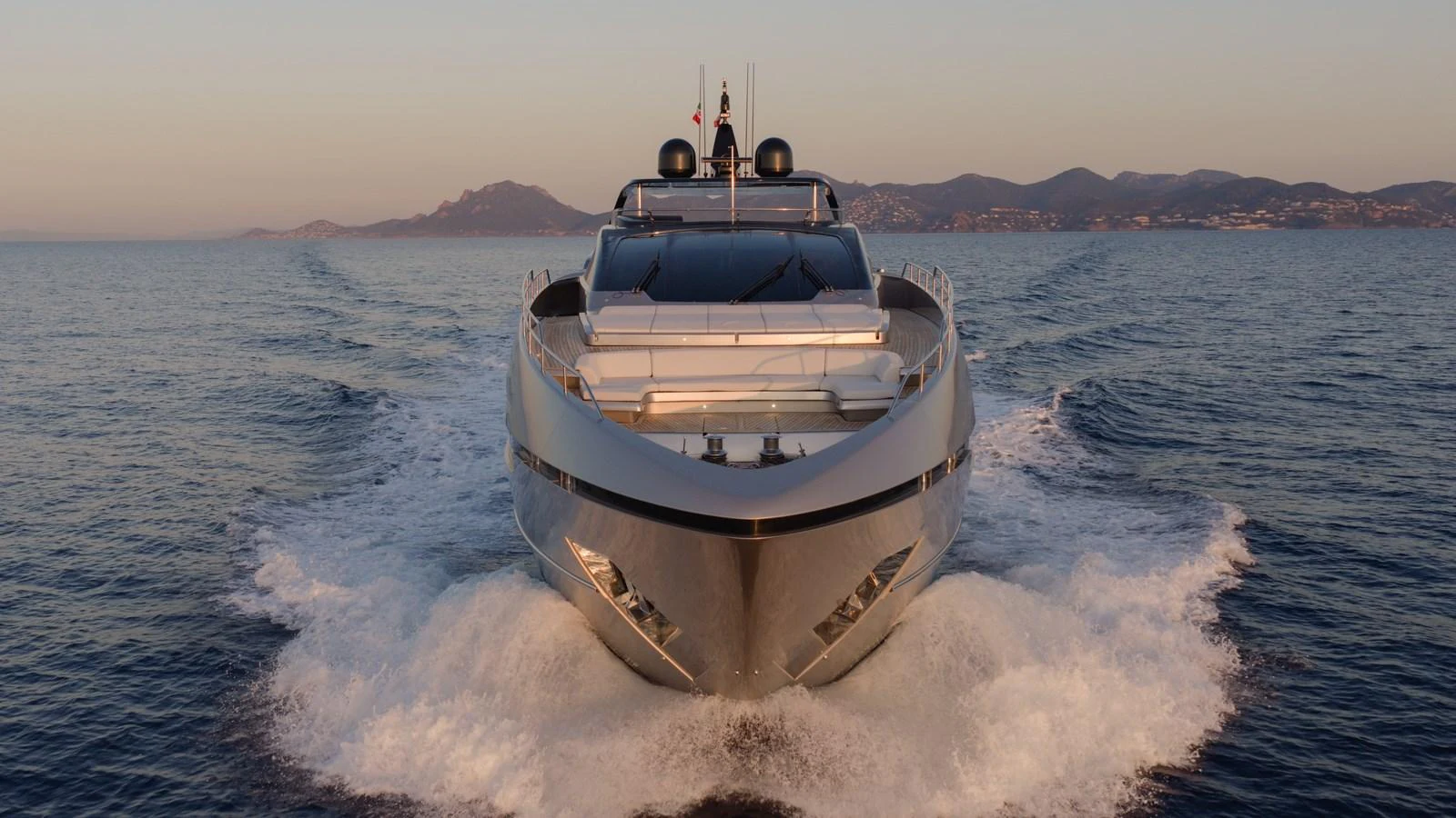 A sleek yacht cruises forward on calm waters with a scenic coastline in the background. aboard M Yacht for Sale