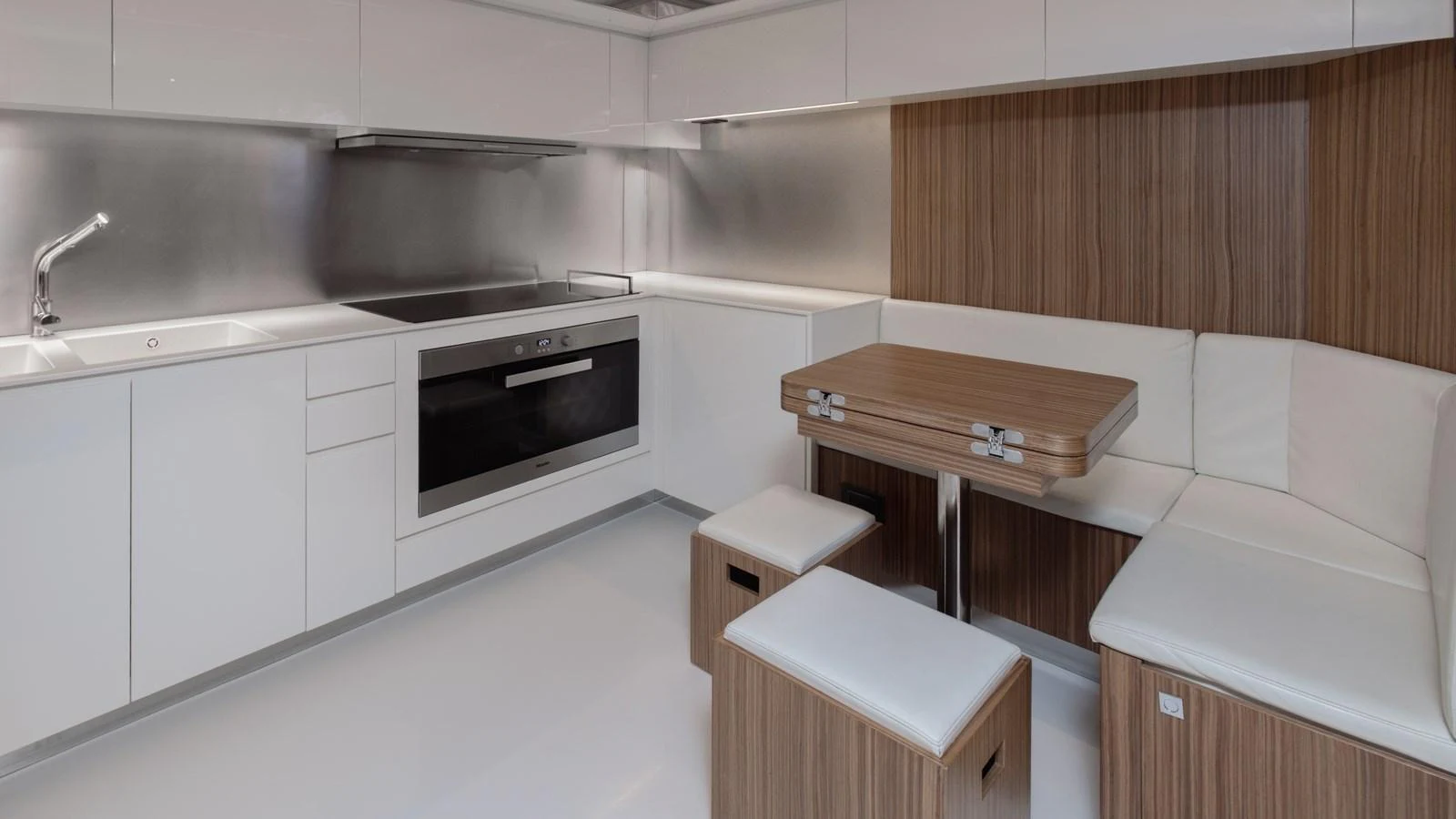 The modern galley features sleek cabinetry, a built-in oven, and a cozy dining nook. aboard M Yacht for Sale