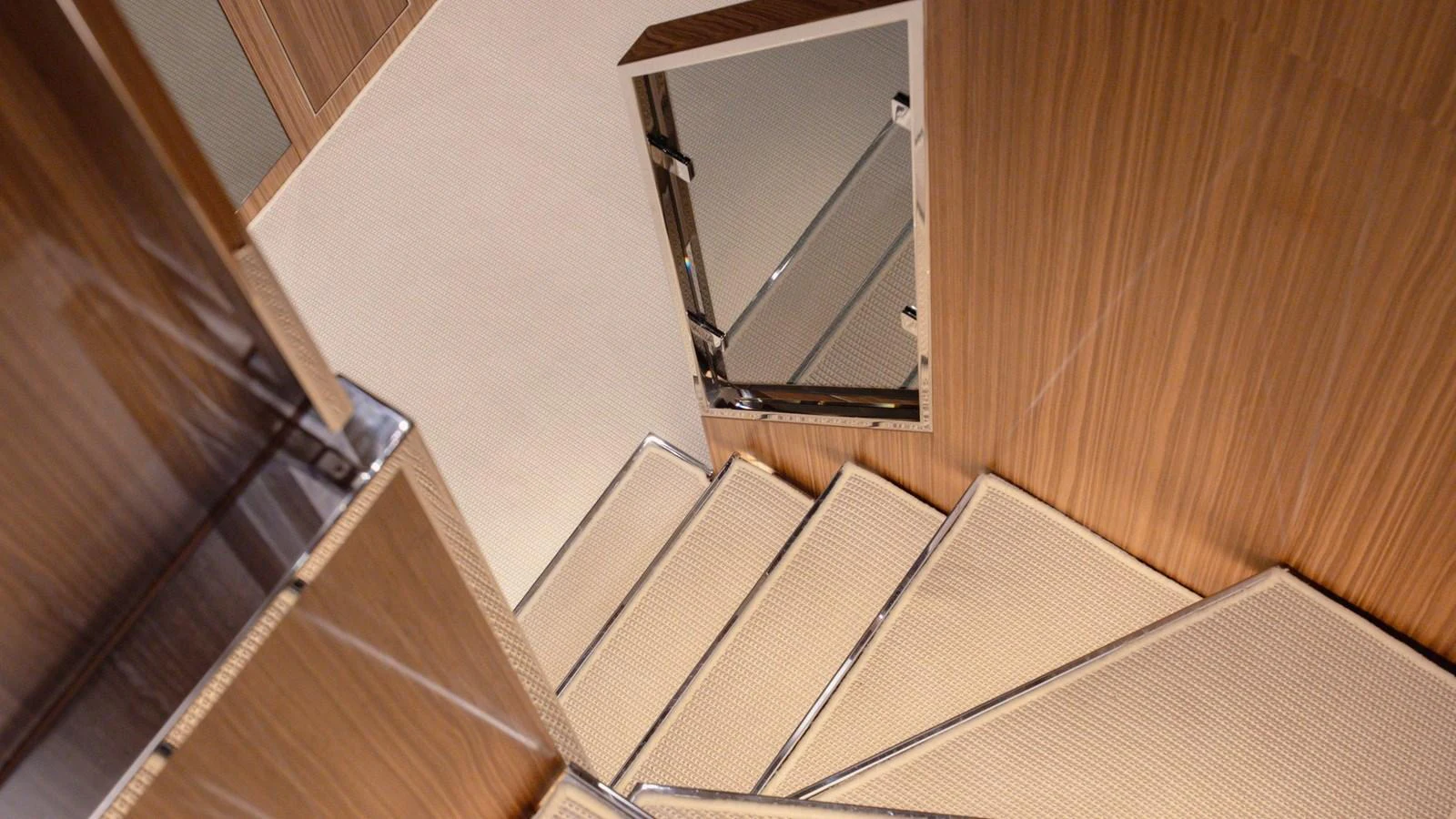 A modern staircase with wooden paneling and carpeted steps leads to the lower deck. aboard M Yacht for Sale