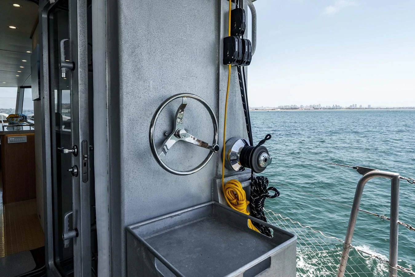 A close-up view of a yacht's exterior detail featuring a winch and a steering wheel. aboard UGLY BETTY Yacht for Sale