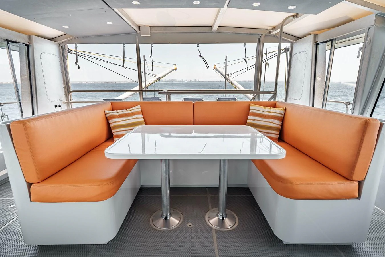 The salon features a cozy seating area with vibrant orange cushions and a sleek white table, offering a perfect spot for relaxation and socializing. aboard UGLY BETTY Yacht for Sale