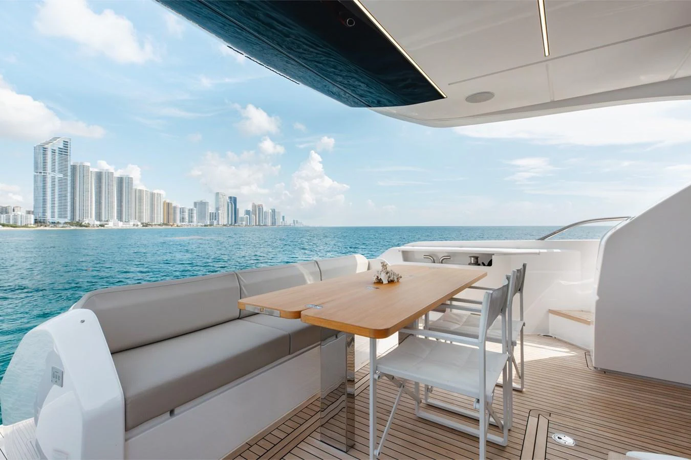 The aft deck offers a serene dining area with stunning ocean views and a backdrop of city skyscrapers. aboard KATRIN I Yacht for Sale