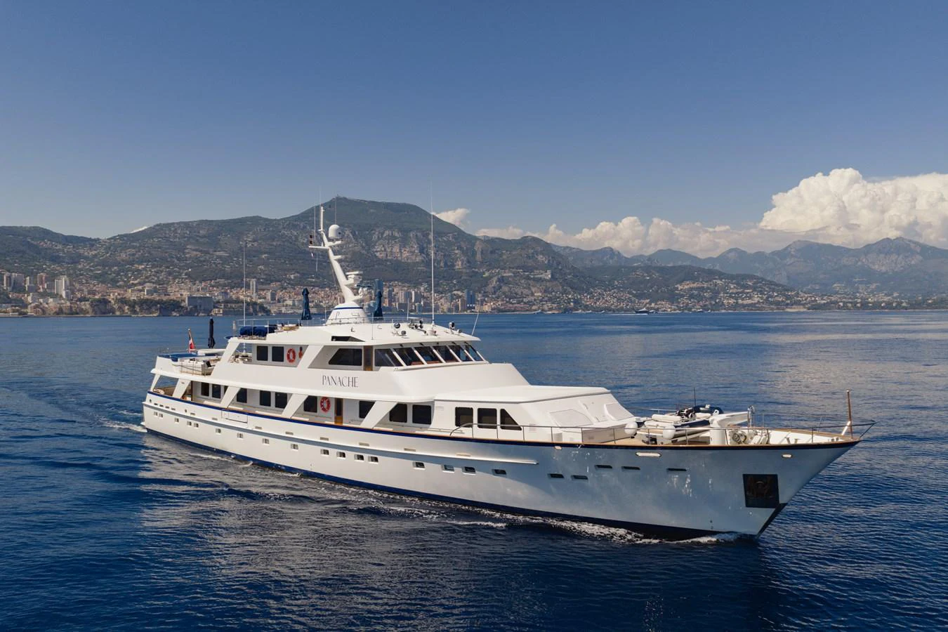 A classic yacht cruises gracefully on calm waters with a scenic coastal backdrop. aboard PANACHE Yacht for Sale