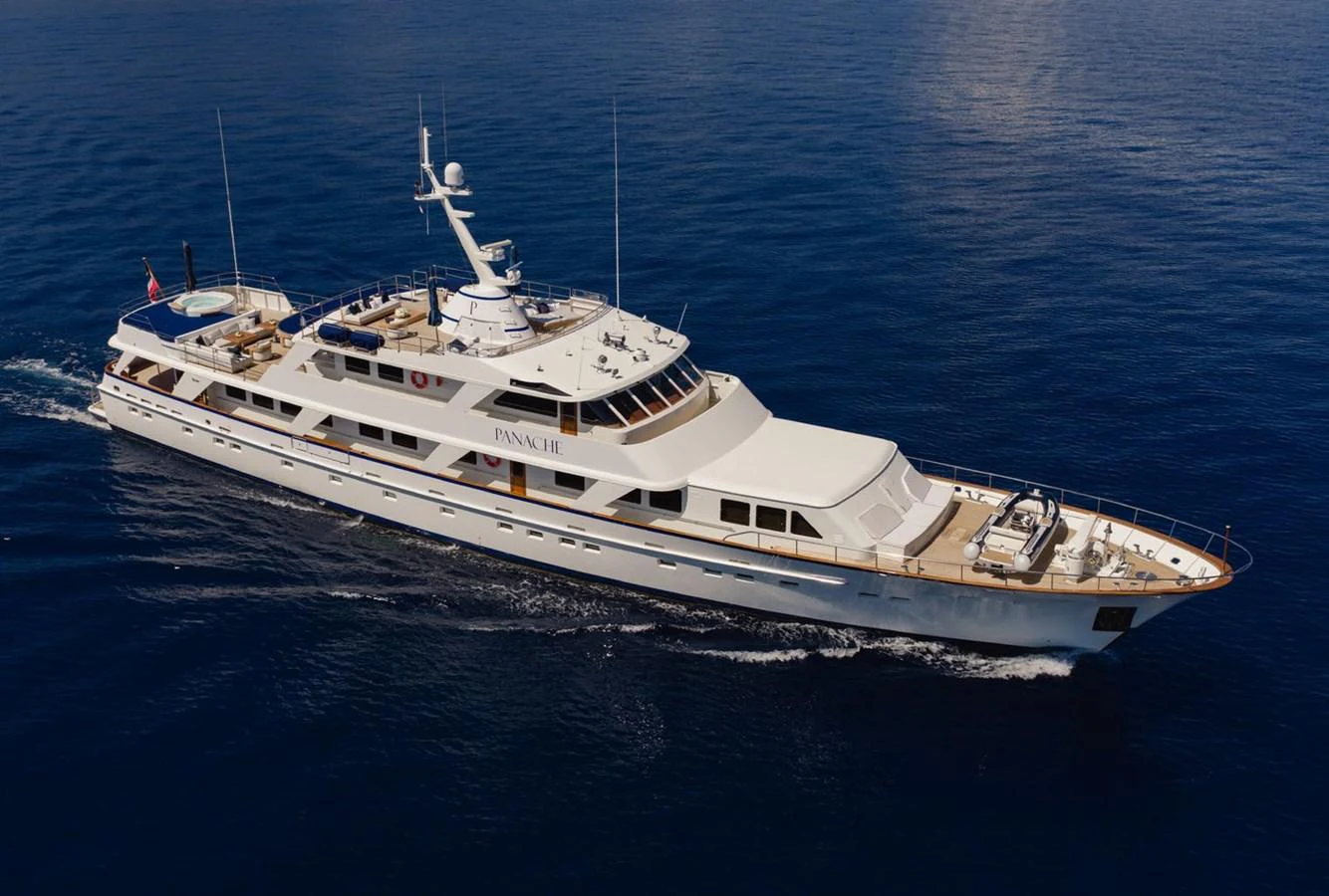 A luxurious yacht glides gracefully over calm blue waters, showcasing its elegant design and spacious decks. aboard PANACHE Yacht for Sale