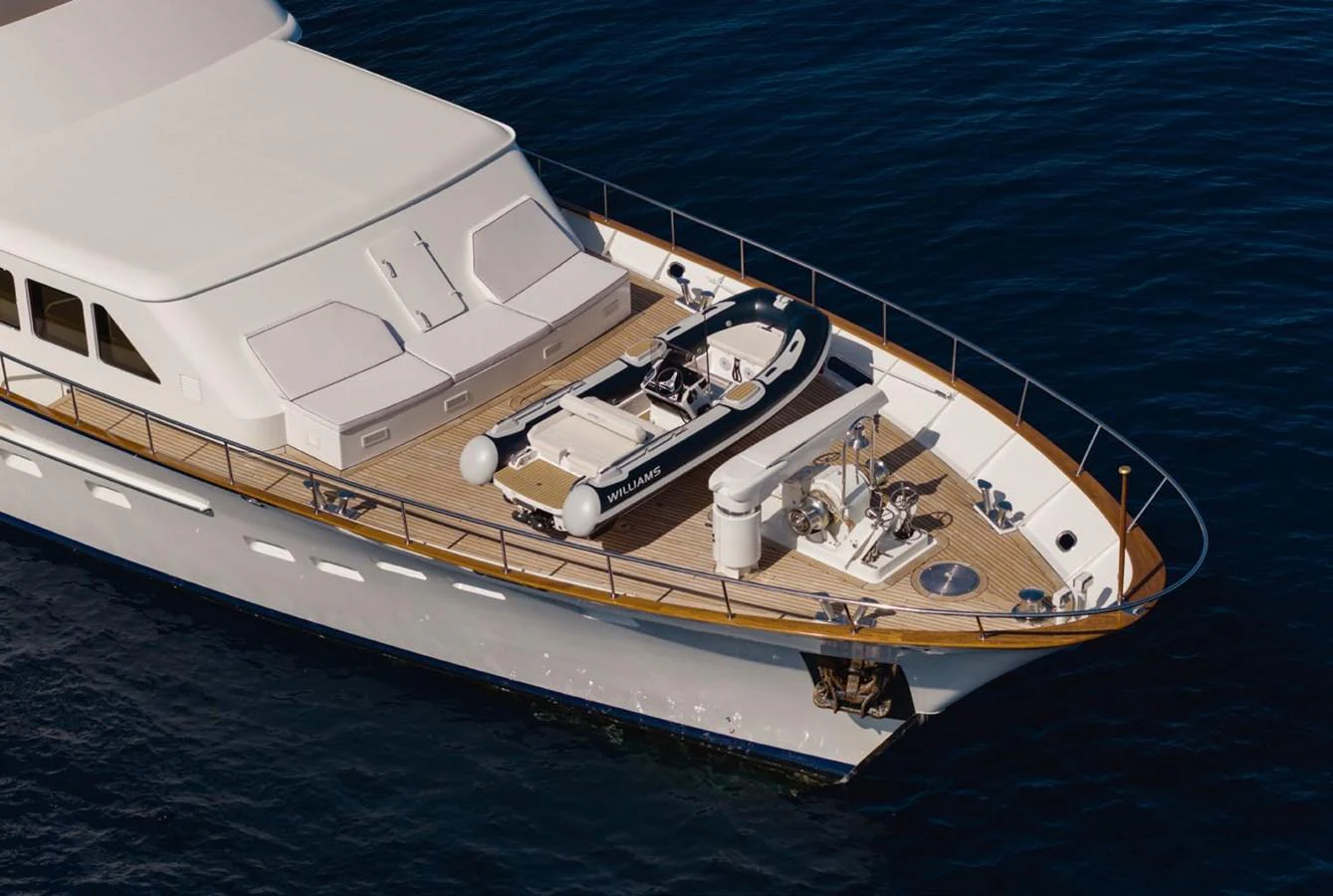 The foredeck of the yacht features a tender and ample lounging space, set against a serene ocean backdrop. aboard PANACHE Yacht for Sale