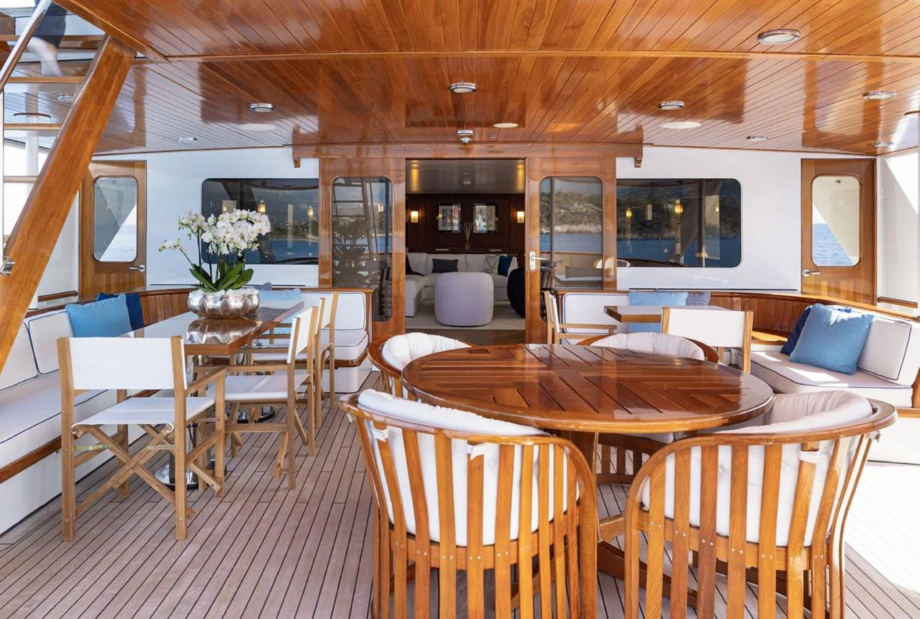 The aft deck features elegant wooden furniture and ample seating for a luxurious outdoor dining experience. aboard PANACHE Yacht for Sale
