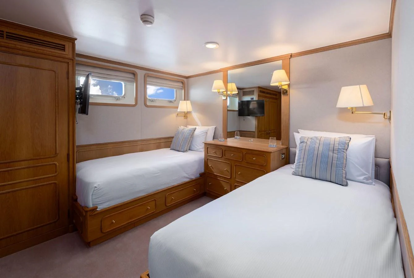 A cozy guest stateroom with twin beds and warm wooden accents. aboard PANACHE Yacht for Sale